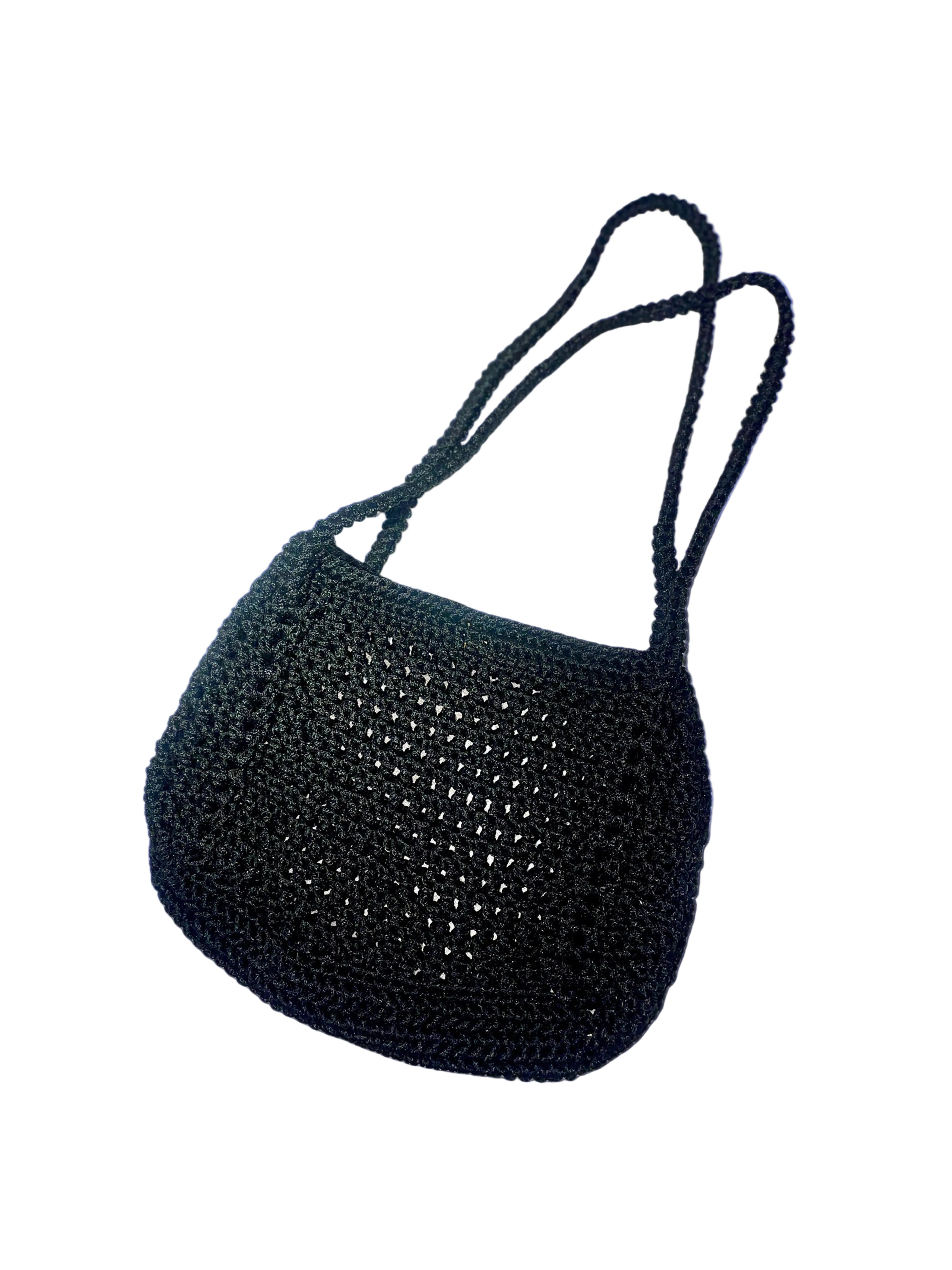 A black crocheted shoulder bag with long thin straps, shown on a solid periwinkle blue background with a soft drop shadow.